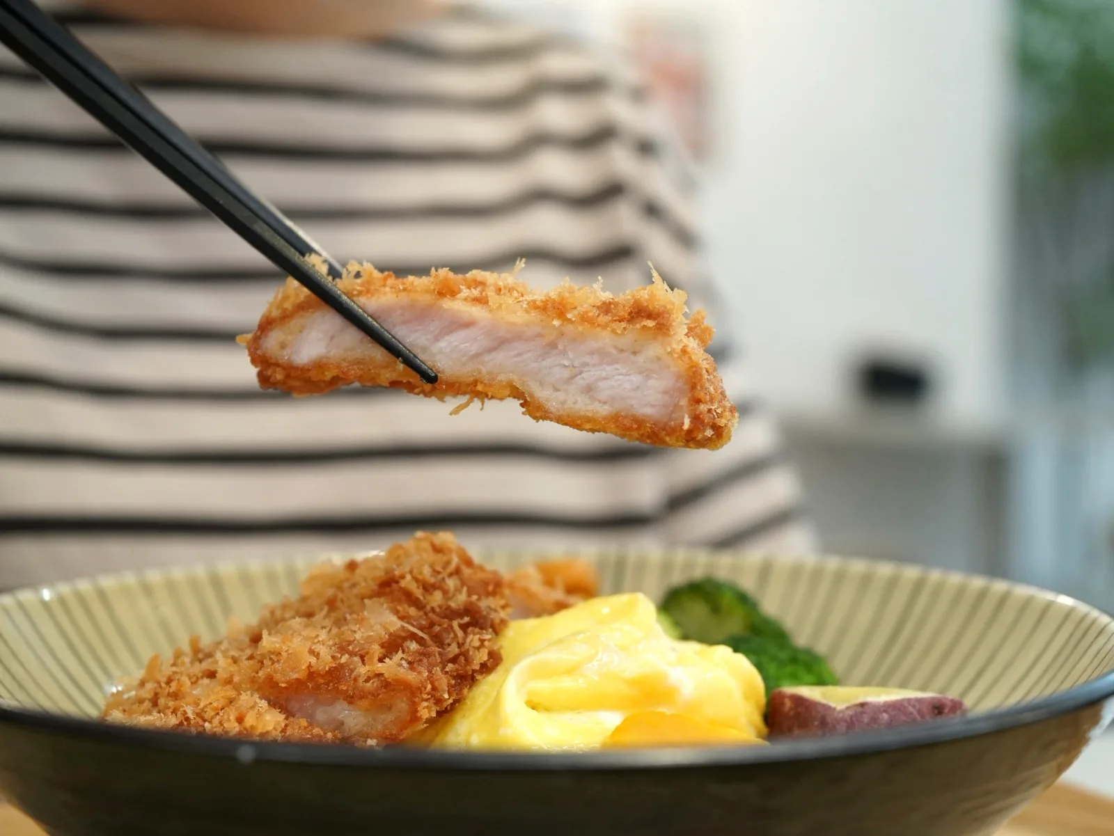 筷子夾起寶煲炸豬排斷面特寫，外酥內嫩